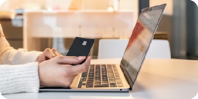 Persona pagando en línea con su tarjeta frente al computador