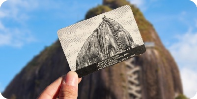 Mano sosteniendo una entrada frente a la Piedra del Peñol